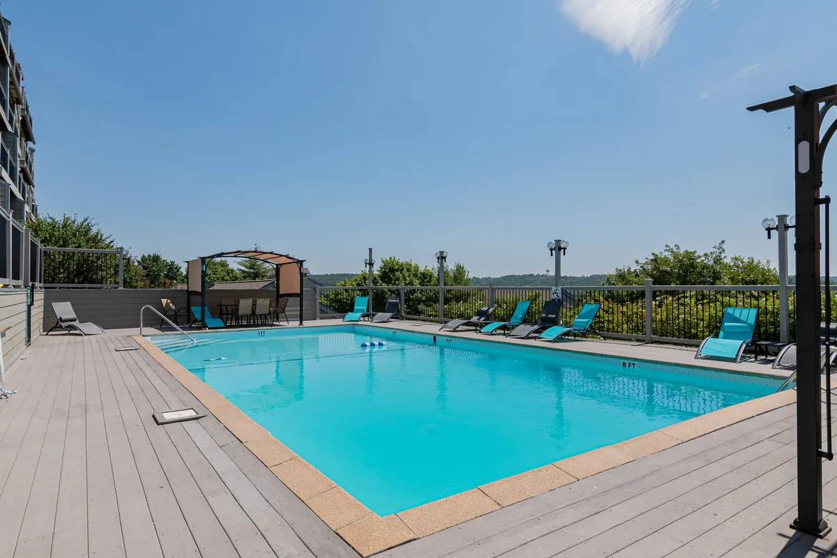 A vibrant exterior shot of the resort’s swimming pool, framed by lounge chairs and a canopy structure, with lush greenery in the background. The pool area is inviting and spacious, ideal for group relaxation and social gatherings.