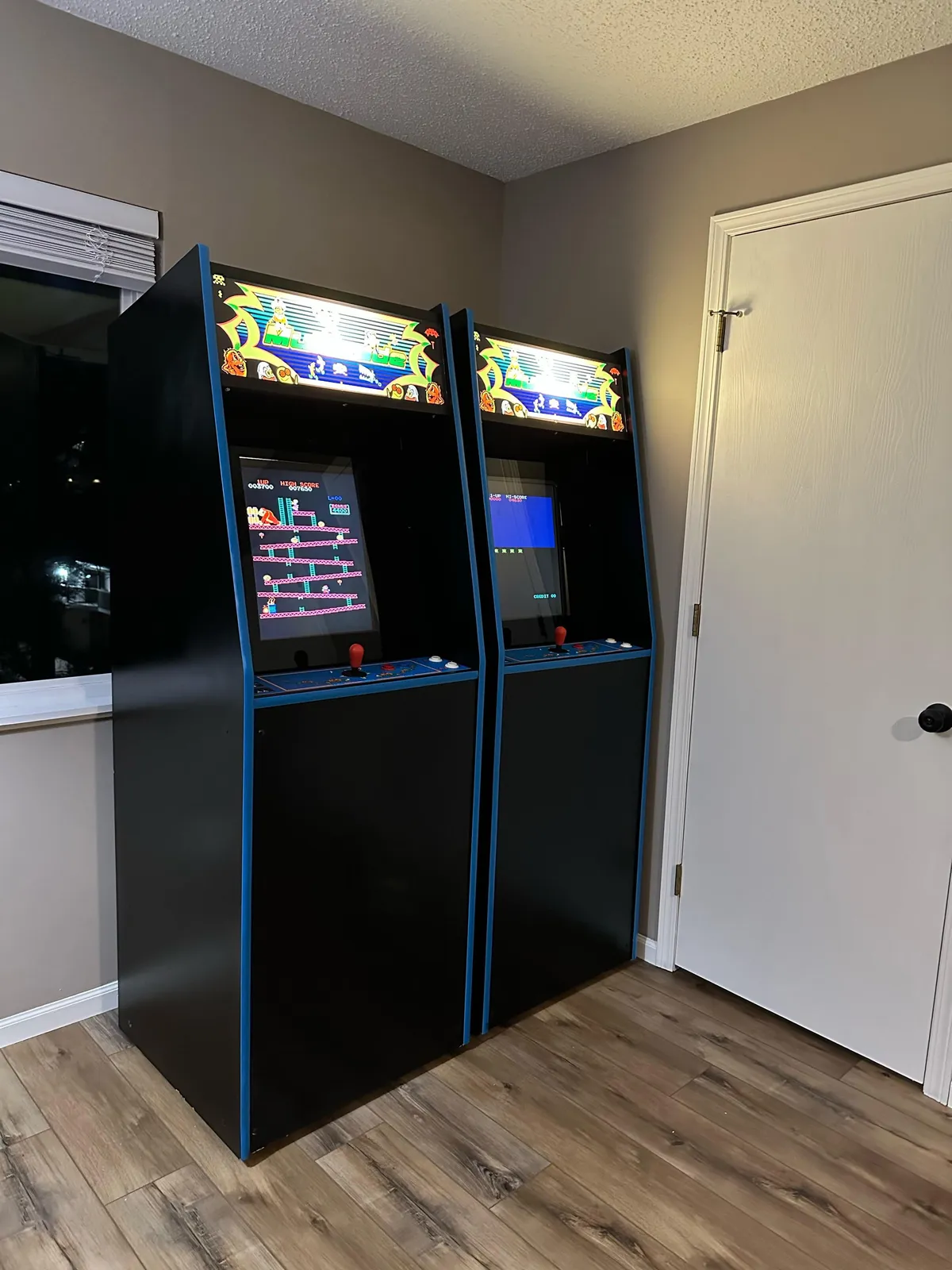 This image features a lofted interior space with visible arcade machines and a large window, creating a playful, casual atmosphere. People are engaged in playing arcade games, socializing, and enjoying friendly competition.