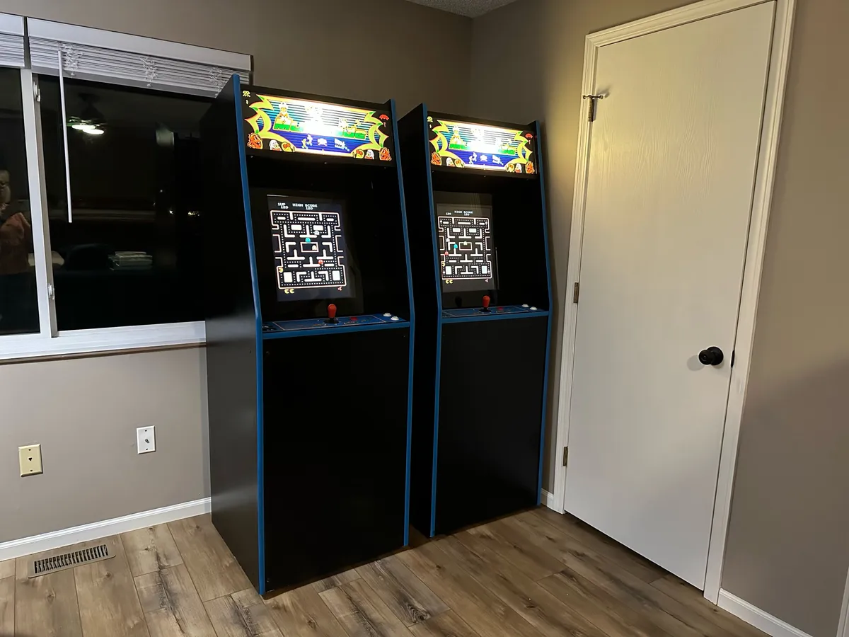 This interior shot highlights two arcade game cabinets, a sunlit window, and a door, with the inviting sense of a dedicated game area. The space appears bright and open, perfect for gaming and relaxing with friends or family.