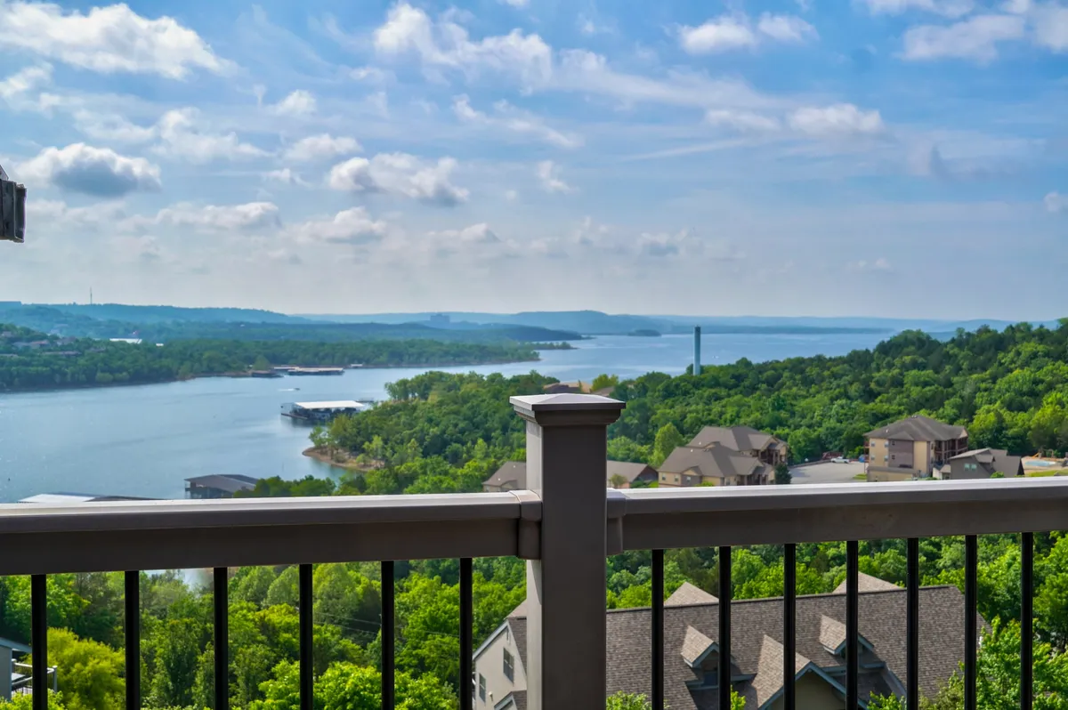 This view showcases an expansive water scene with lush greenery and distant hills, all visible from an elevated vantage point. The mood is tranquil, ideal for stargazing or hosting a sunset barbecue on the deck.