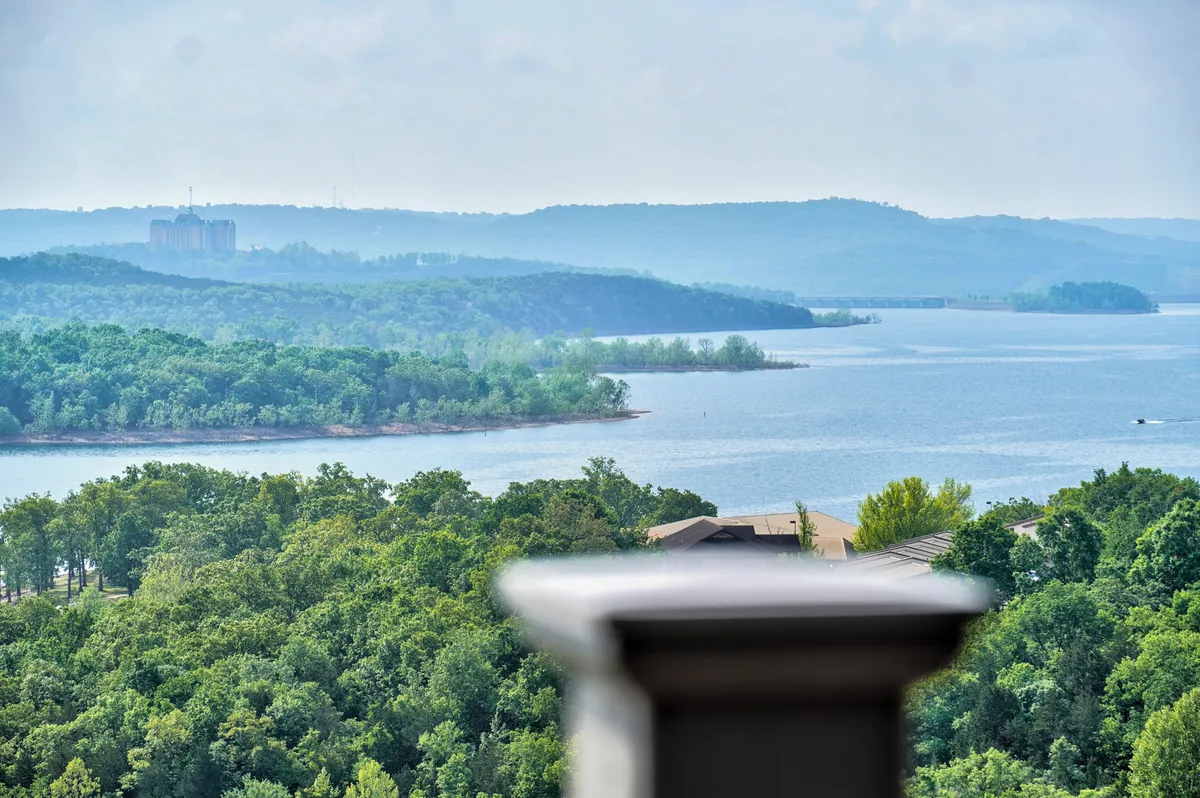 A tranquil view over a calm lake, surrounded by lush greenery and distant hills. The scene captures the serene beauty of the landscape, inviting guests to enjoy activities like boating, fishing, or simply relaxing together outdoors.