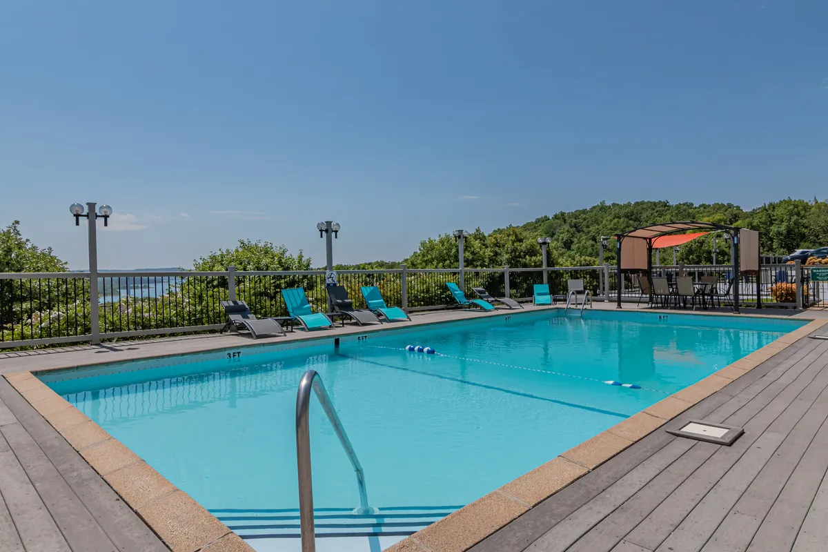 A sparkling outdoor swimming pool surrounded by lounge chairs and a canopy seating area, set against a lush backdrop. The pool is inviting and reflects the family-friendly, fun atmosphere highlighted in the text.