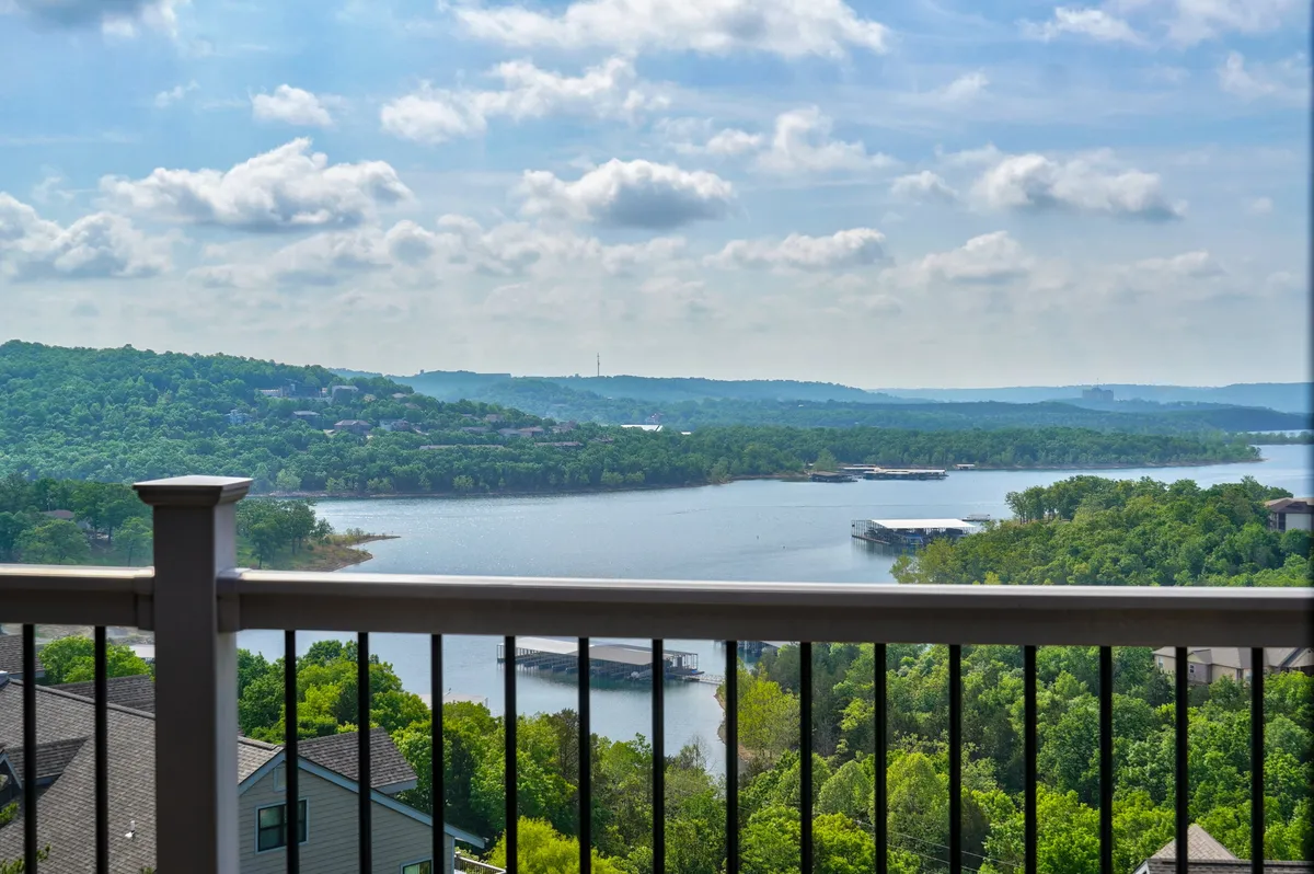 An expansive water view featuring lush greenery, rolling hills, and a serene cloudy sky, suggesting opportunities for boating, fishing, and nature walks along the lakeshore.