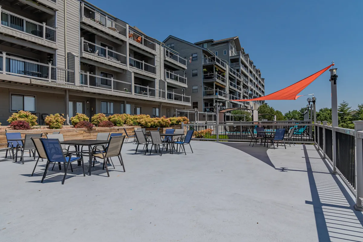 An inviting exterior seating area is surrounded by vibrant flowers and shaded by an orange sail, offering a space for outdoor dining or simply relaxing in the sun. The setup encourages social gatherings and taking in the natural beauty around the property.
